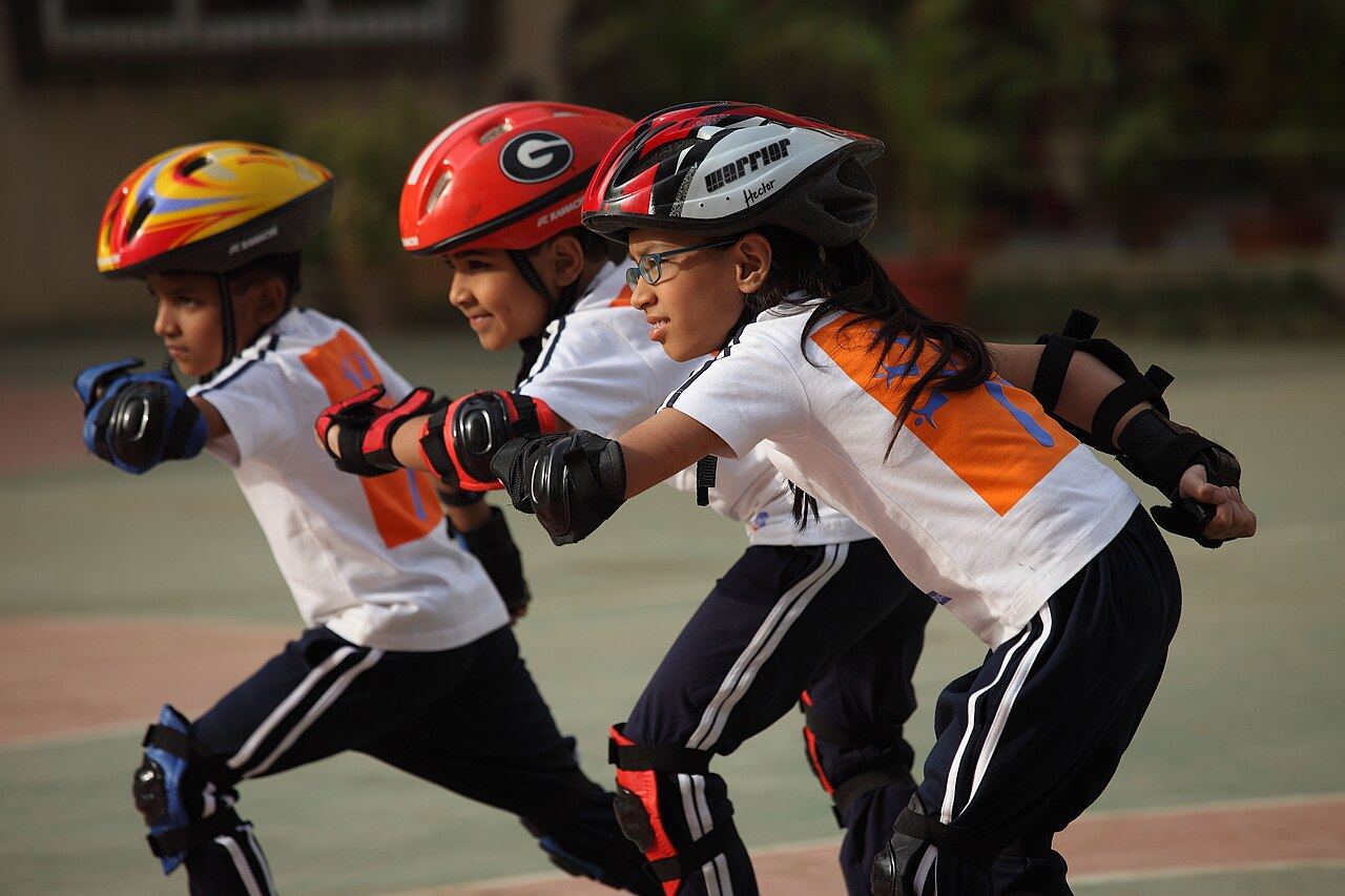 Young skaters in helmets and pads lined up on the rink